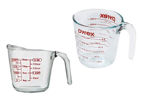2 glass measuring cups by Pyrex and Anchor Hocking on a white background