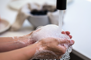 close up image of 2 hands full of soap suds under a faucet with running water