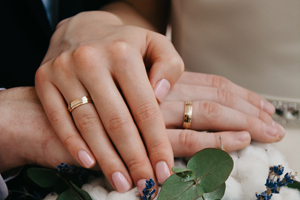 wedding rings on 2 hands with flowers under them